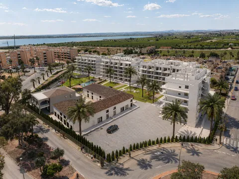 Luftbild-Visualisierung von Oasis Garden mit dem ziegelgedeckten Gebäude im Vordergrund, dahinter die weißen Wohngebäude und Gärten, in der Ferne die Lagune